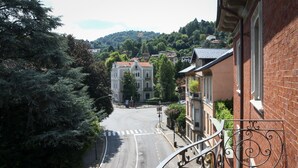 A street view with a building featuring a balcony with ornate metal railings. - LuxRent Penthouse Crimea (Turin)
