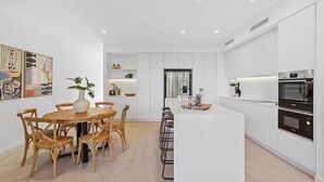 Una cocina moderna con armarios blancos, una isla central y un comedor con sillas de madera y una mesa redonda.
