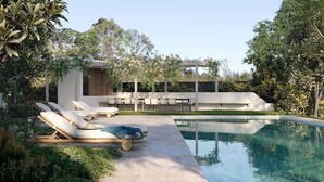 Un área de piscina moderna al aire libre con sillones de descanso y una pérgola.