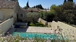 A courtyard with a swimming pool, stone walls, and traditional tiled roofs.