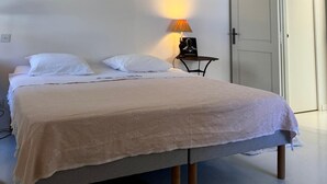 A bedroom with a bed, a nightstand, a lamp, and a door.