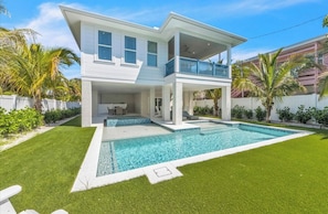 A two-story house with a swimming pool, a covered patio, and a well-maintained lawn. - Amazing AMI House! Heated pool and hot tub! (Anna Maria)