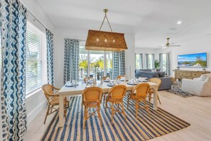 A dining area with a long table, chairs, and a hanging light fixture.