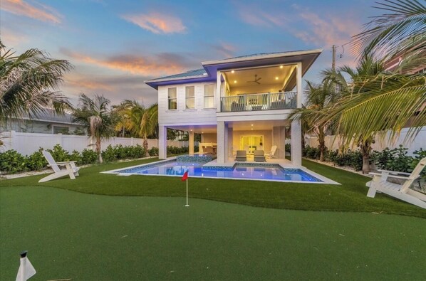 A two-story house with a swimming pool, a balcony, and a well-maintained lawn.
