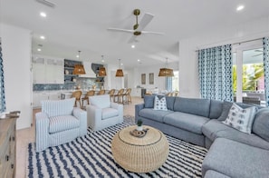 A modern living room with a grey sofa, striped armchairs, and a round coffee table. - Amazing AMI House! Heated pool and hot tub! (Anna Maria)