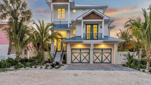 A two-story house with a balcony, a garage, and a driveway. - Amazing 6 bed house on Anna Maria! Putt putt, heated pool and spa! (Anna Maria)