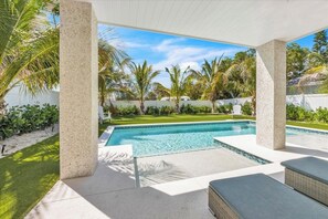A poolside area with a clear view of the pool, surrounded by palm trees and a well-maintained lawn.