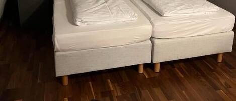 A twin bed with a headboard, a bedside table, and a lamp.