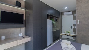 Una cocina compacta con microondas integrado, refrigerador y pileta.