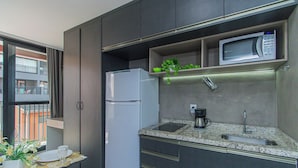 Cocina compacta con refrigerador, microondas y cafetera.