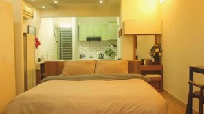 A bedroom with a bed, a nightstand, a chair, and a view of a kitchen. - 57P3F-SweetHeart in SaiGon (Thành phố Hồ Chí Minh)