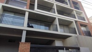 A multi-story building with balconies, a brick base, and a large glass door.