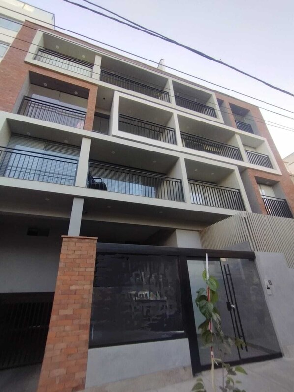 A multi-story building with balconies, a brick base, and a large glass door.