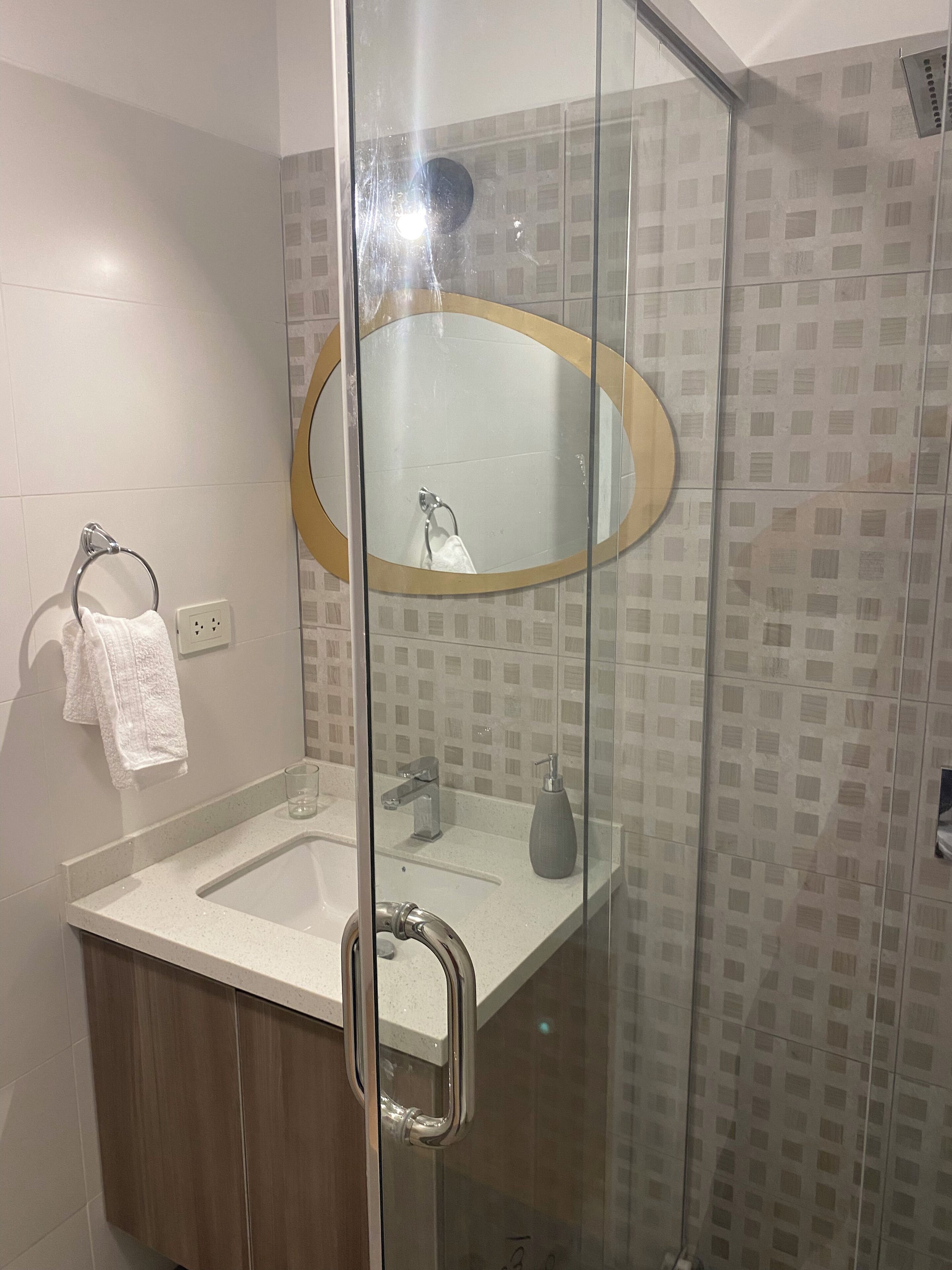 Uma casa de banho moderna com cabine de duche em vidro, lavatório com espelho e barra de toalhas.