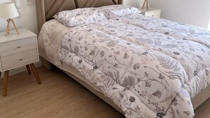 A bedroom with a bed, a nightstand, a lamp, and a wall-mounted phone.