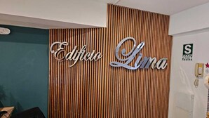 A reception desk with a wooden slat wall and a sign that reads "Edificio Lima".