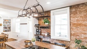 A kitchen with a wooden island, brick walls, and a hanging light fixture. - The River House-- Secluded, Serene, Hot tub & Firepit (Bellbrook)
