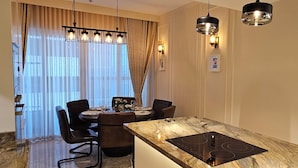 Un comedor moderno con una mesa de mármol, sillas negras e iluminación colgante.