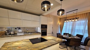 Una cocina moderna con una isla grande, electrodomésticos integrados y un comedor con una mesa dispuesta para cuatro.