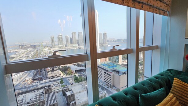 Una habitación con un ventanal grande que ofrece vistas a un paisaje urbano con edificios altos y zonas de construcción.