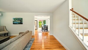 A spacious living room with a wooden floor, a beige sofa, and a painting on the wall.