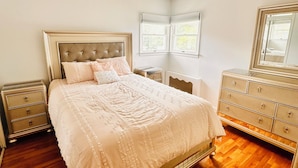 A bedroom with a bed, nightstands, dresser, and a window. - Spacious 5BR Home Private Backyard Basket Ball Hoop Near NY& Long Island Beaches (Syosset)