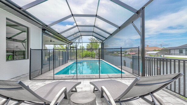 A covered outdoor swimming pool with lounge chairs and a view of the surrounding area. - VILLA BRILLANTE, A BRAND NEW Luxury Waterfront home  Pool/Spa & Gulf Access (Cape Coral)