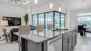 A modern kitchen with a large island, stainless steel appliances, and a glass backsplash. - VILLA BRILLANTE, A BRAND NEW Luxury Waterfront home  Pool/Spa & Gulf Access (Cape Coral)