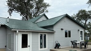 A single-story house with a front door, a small porch, and a table with chairs. - Rogers Creekside Ranch - Wessington Springs, SD - 3+ Bed, 1 Bath (Wessington Springs)