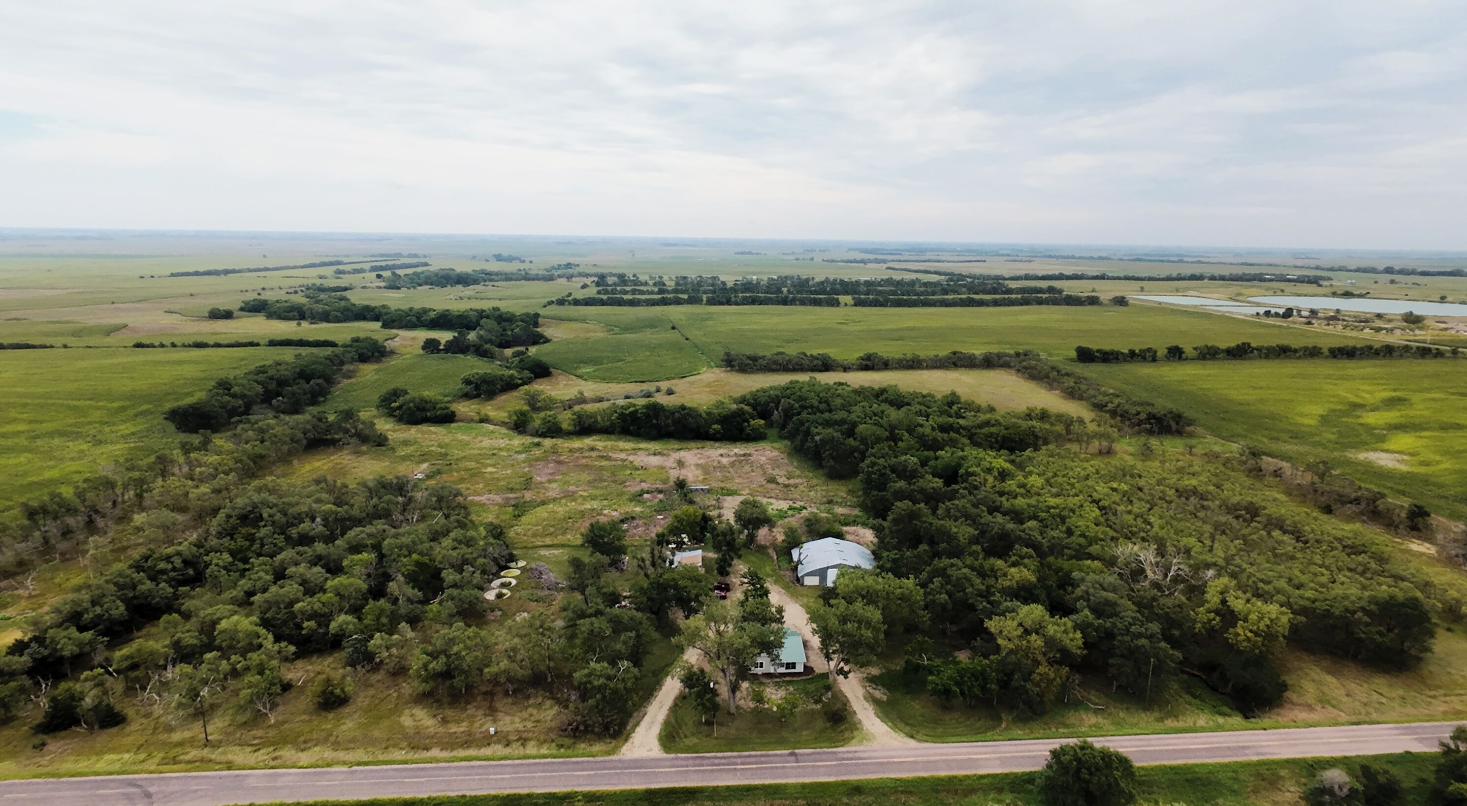 An aerial view of a rural property with a house surrounded by fields and trees.