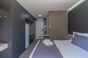 Una habitación de hotel moderna con cama, kitchenette y baño.