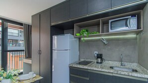 Een kleine keuken met een koelkast, magnetron en koffiezetapparaat.