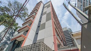 Een hoog gebouw met een modern architectonisch ontwerp, meerdere balkons en een gevel met een rasterpatroon.