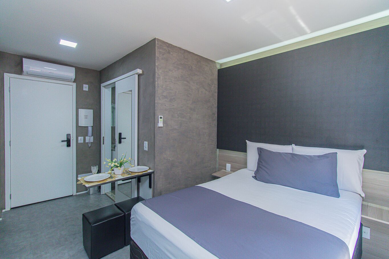 Ein modernes Hotelzimmer mit Bett, Nachttisch und Spiegel.