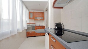 Una cucina moderna con mobili in legno, forno integrato, lavello e piano cottura a induzione nero.