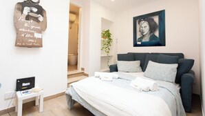 A modern bedroom with a large bed, a small bedside table, a framed artwork, and a wall-mounted piece of art. - Luminous apartment with private terrace in the colosseum (Roma)