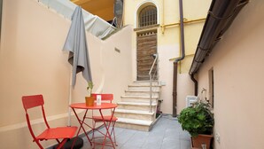 A narrow outdoor area with a red folding chair, a small round table, and a potted plant. - Luminous apartment with private terrace in the colosseum (Roma)