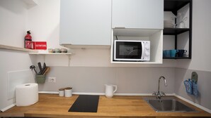 A kitchen with a wooden countertop, a stainless steel sink, a microwave, and a shelf with kitchen utensils. - Luminous apartment with private terrace in the colosseum (Roma)