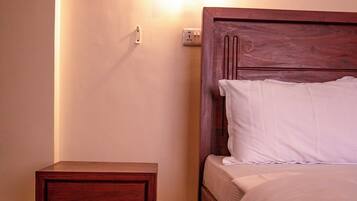 A neatly made bed with a wooden headboard and a nightstand with drawers.