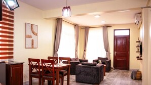 Un salon comprenant un coin repas, un ensemble de canapés, une table en bois avec des chaises et une porte.