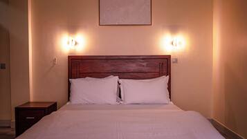 Una cama bien hecha con cabecera de madera y dos lámparas de noche.