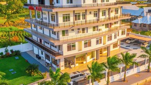 Un hôtel à plusieurs étages, doté d’un toit rouge, de balcons et d’un jardin aménagé.