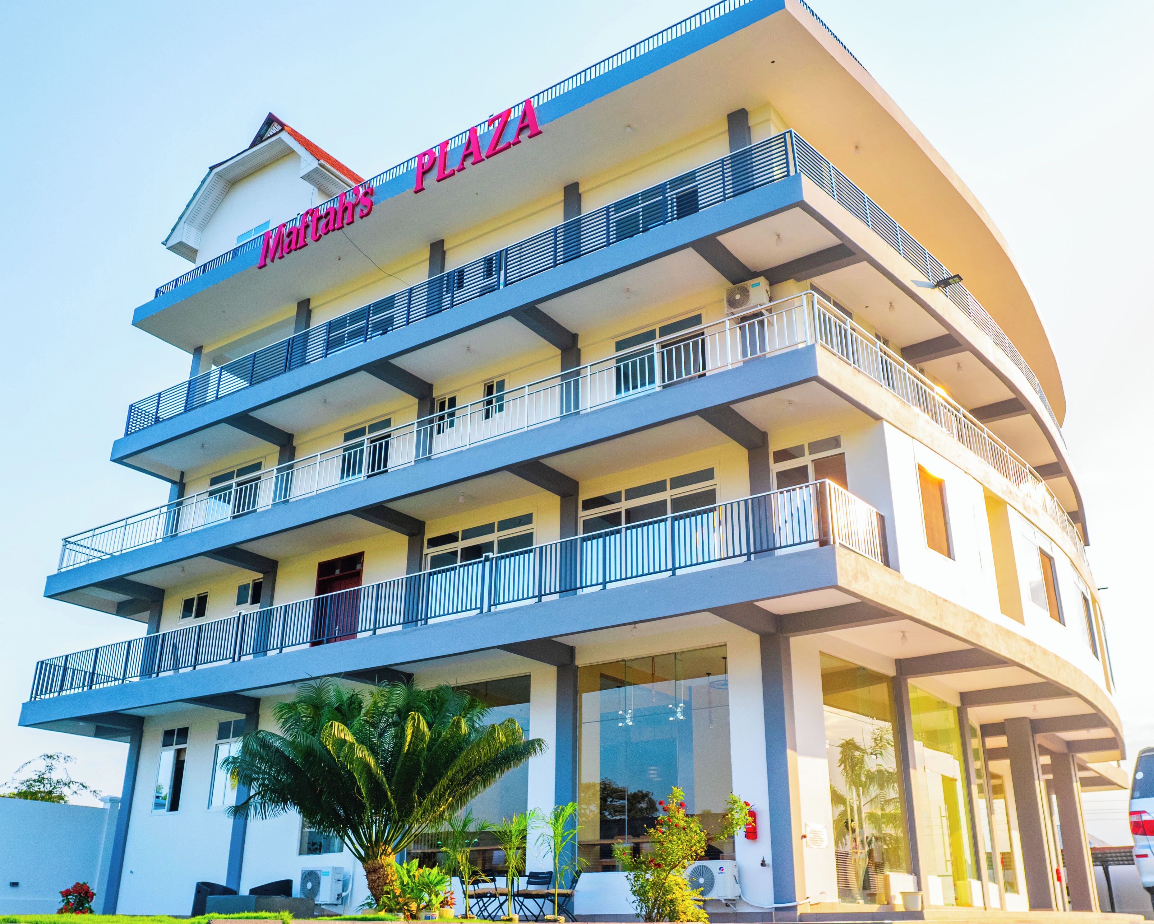 A multi-story hotel with a prominent 'Mahatma's Plaza' sign, balconies, and a covered entrance area with seating.