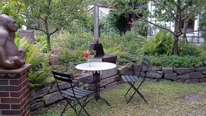 En terrasse med en statue, et rundt bord og to stole.