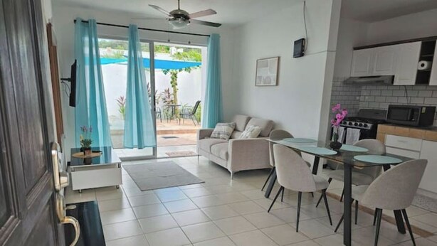 A modern living room with a sofa, dining table, and chairs. There is a kitchen area with cabinets and appliances. - Welcome to your tropical getaway! 6 people (Herradura)