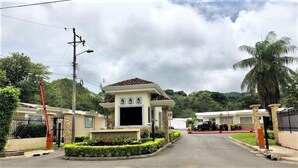 A residential area with a gated entrance, a house with a tiled roof, and a palm tree. - Welcome to your tropical getaway! 6 people (Herradura)