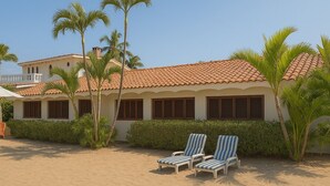 A beachfront property with a tiled roof, palm trees, and two lounge chairs. - BEACHFRONT - 3-bedroom home on the Los Ayala Beach (Los Ayala)
