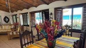 A dining area with a table set for two, a wooden bench, and a vase with colorful flowers. - BEACHFRONT - 3-bedroom home on the Los Ayala Beach (Los Ayala)