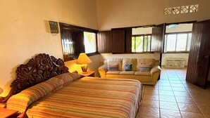 A bedroom with a bed, a nightstand, a lamp, a sofa, and a window with blinds. - BEACHFRONT - 3-bedroom home on the Los Ayala Beach (Los Ayala)