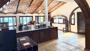 A spacious kitchen with a high ceiling, exposed brickwork, and a large island with modern appliances. - BEACHFRONT - 3-bedroom home on the Los Ayala Beach (Los Ayala)